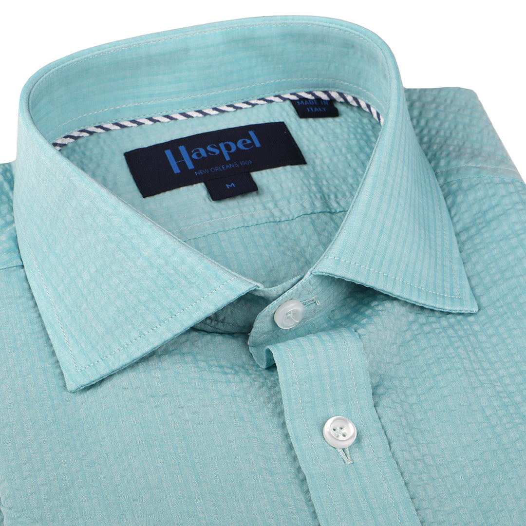 A solid look for a solid guy. The light teal hues of the ocean are calling you in this shirt. Seersucker, lightweight, and supremely cool. Available in short or long sleeve. 100% Cotton Seersucker • Spread Collar • Short Sleeve • Contrast Buttons • Chest Pocket • Machine Washable • Made in Italy