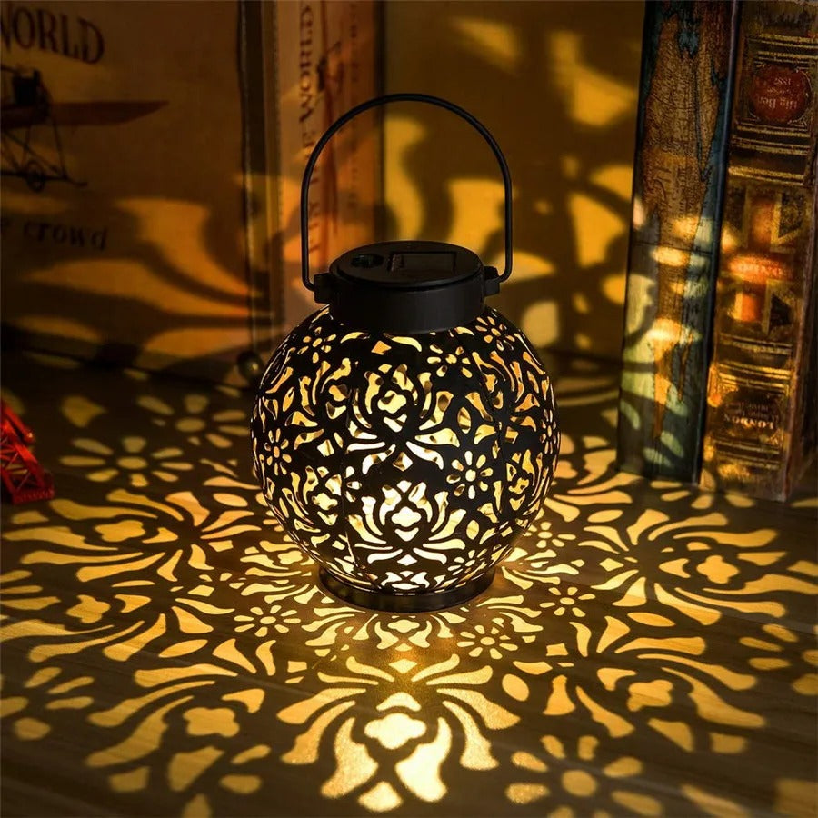 Lanterne solaire LED décorative en fer ajouré posée sur une table de jardin