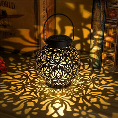 Lanterne solaire LED décorative en fer ajouré posée sur une table de jardin