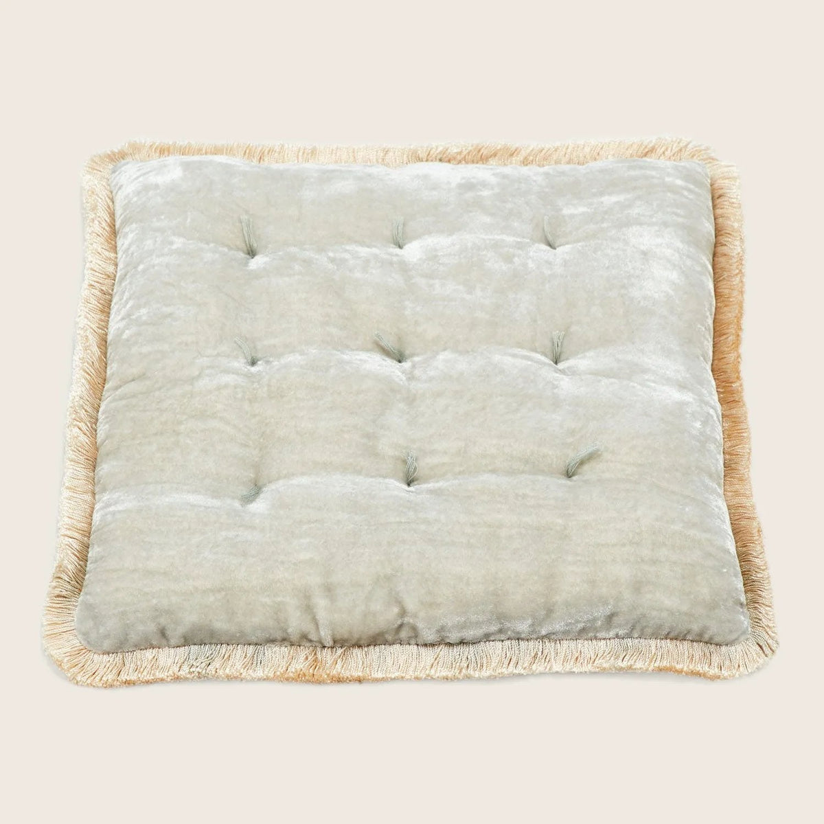 Square tufted pillow with quilted appearance and decorative fringe trim.