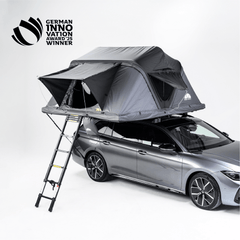 Graues Auto mit Dachzelt und Leiter vor hellem Hintergrund. Text oben links: "GERMAN INNOVATION AWARD '25 WINNER".