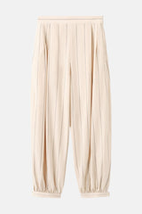 Pantalon écru à rayures de MANGO, en imitation lin avec une coupe ample et des chevilles plissées, porté par un mannequin.