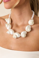 Partial view of the necklace showing a cluster of large white banded tun shells with a hint of mint green, accented by pearl-like beads.