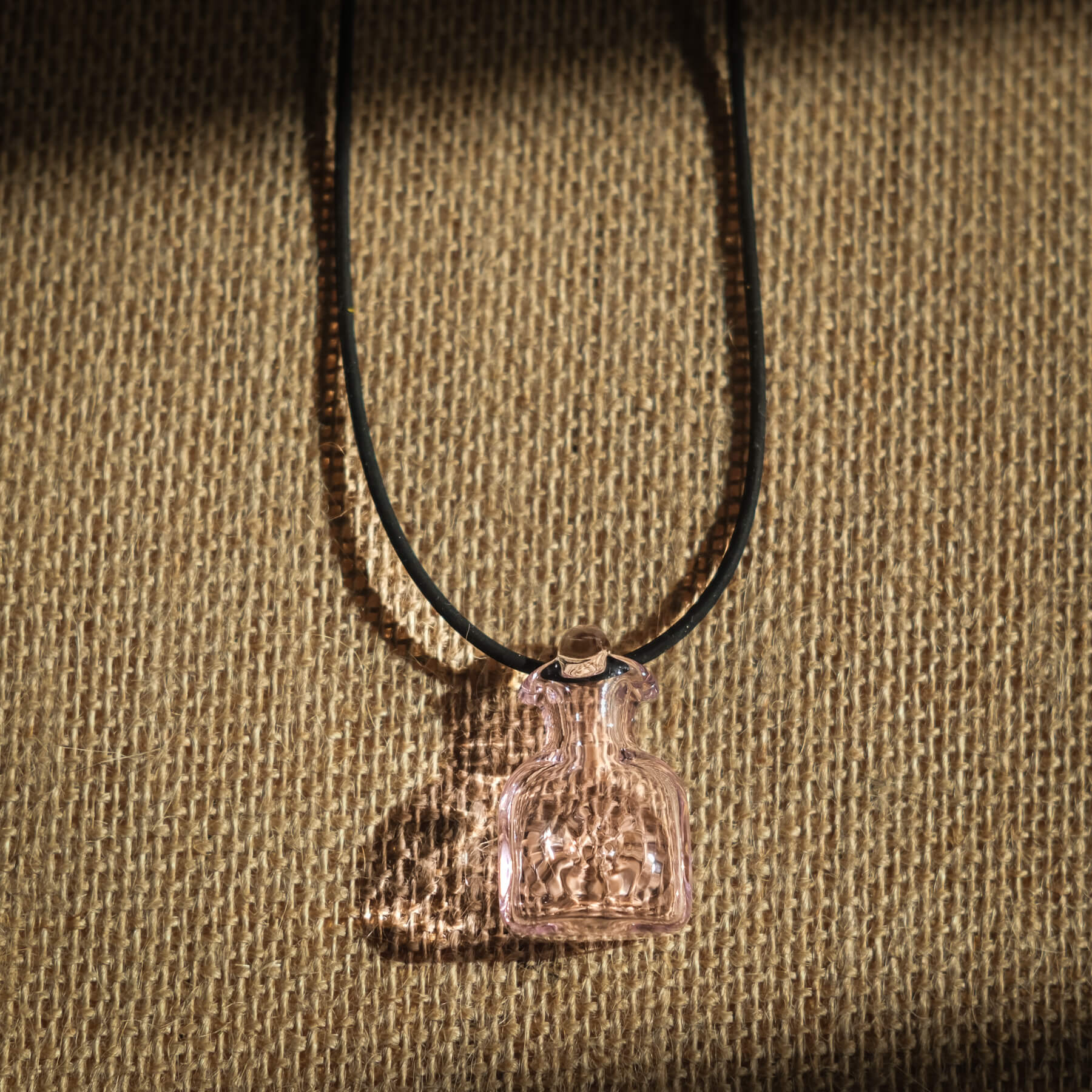 Necklace with two small glass bottles on a textured brown background