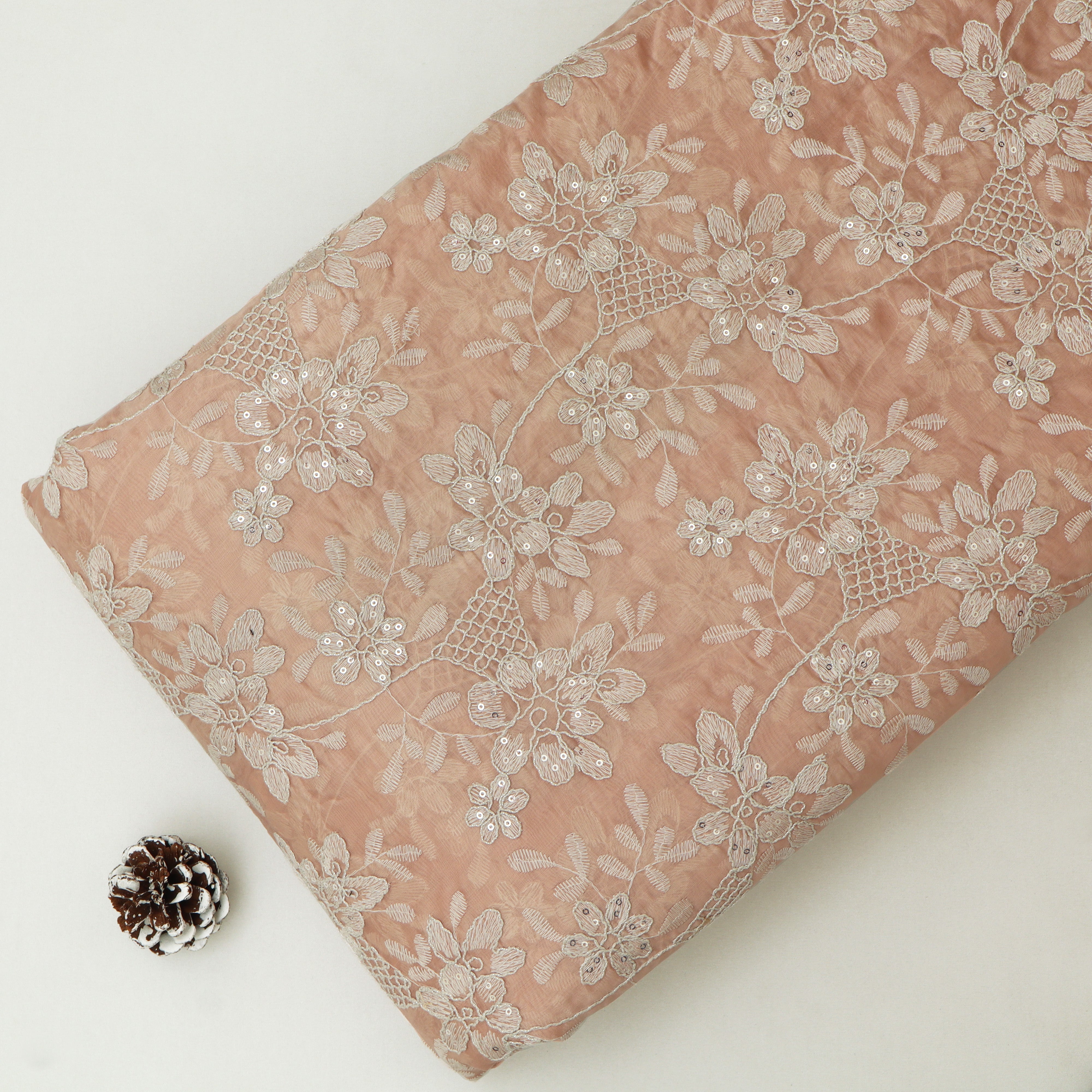 Pink fabric with white floral embroidery on a white background