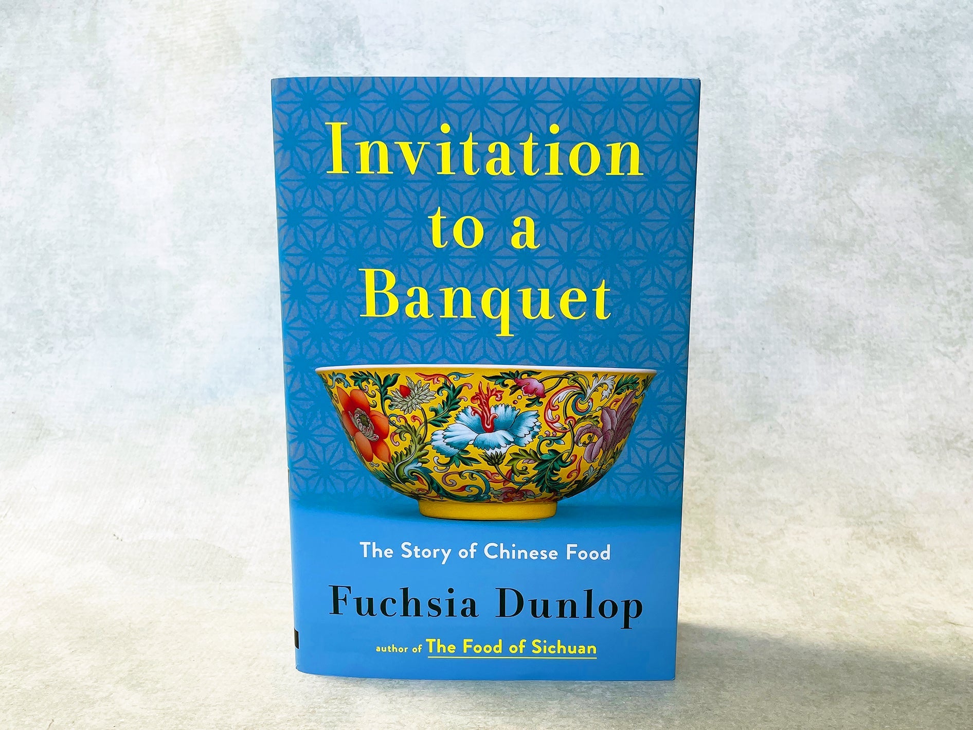 The image shows the front cover of the book titled 'Invitation to a Banquet: The Story of Chinese Food' by Fuchsia Dunlop. The cover features a colorful traditional Chinese bowl design with floral patterns against a blue background.