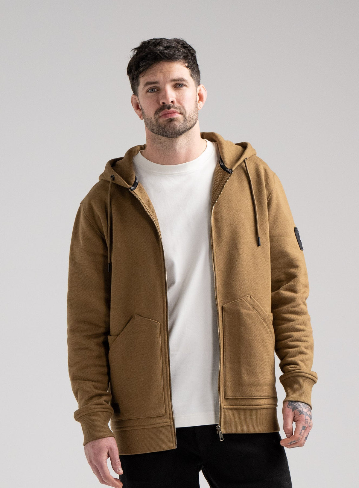 Bernie Is 6ft And Wears Size: M | Hem Studio Image Of Model Wearing Dissident Zipped Hoody In Coyote Brown (SS Model)