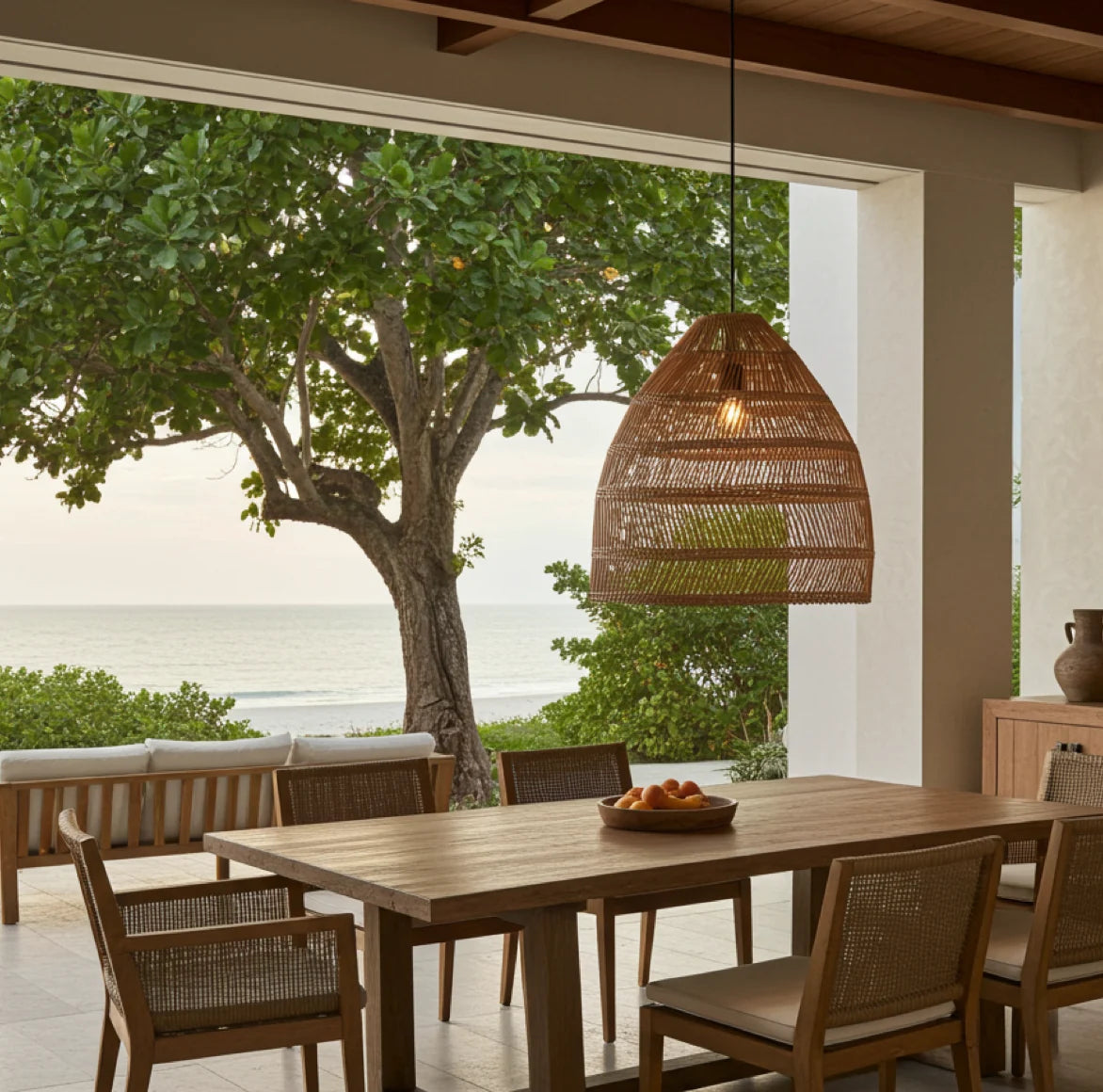 Gemütlich beleuchteter Balkon im Skandi-Stil mit der Rattan Lampe MAJA über einer Sitzgruppe.